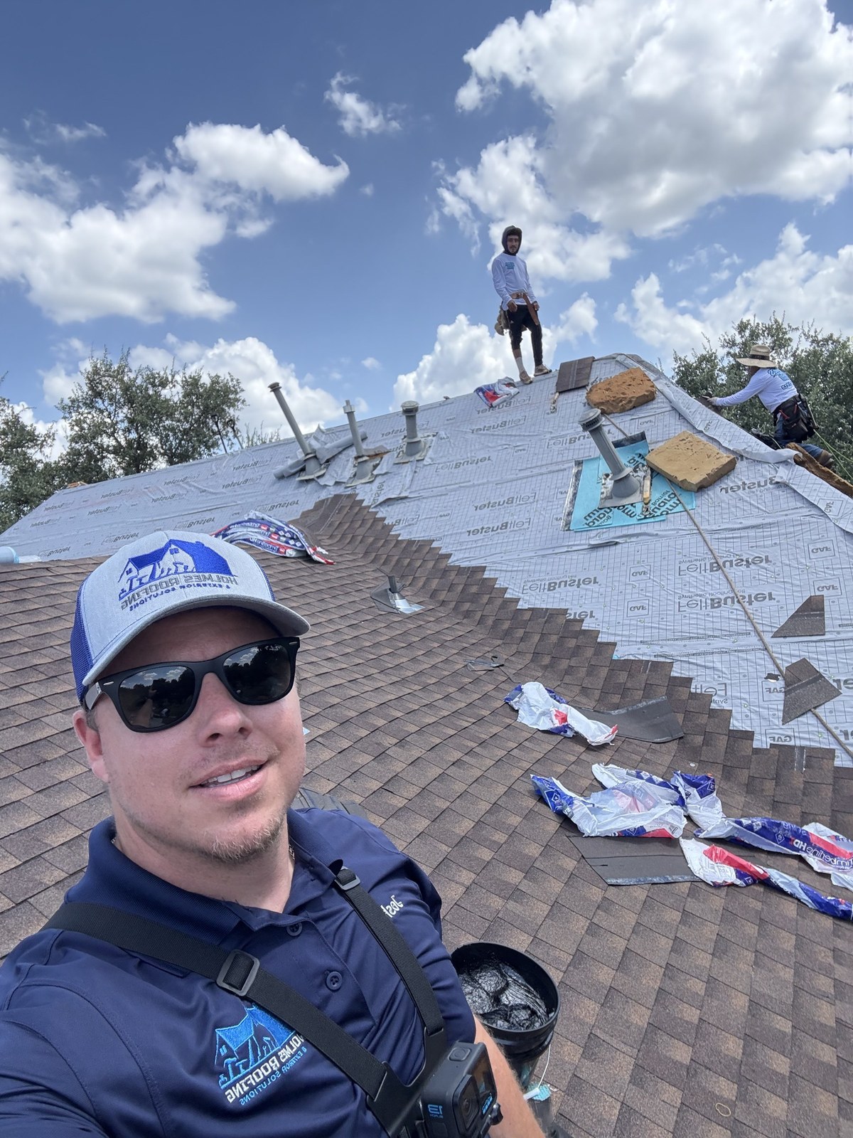 Joshua Holmes and a colleague actively working, rooftop and sky in the background