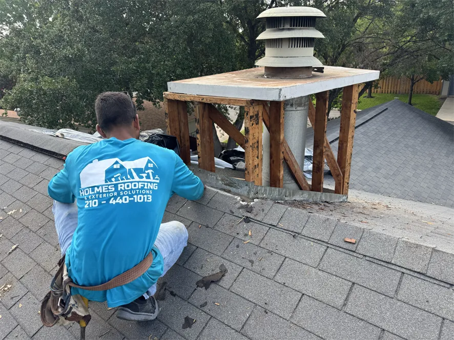 Holmes Roofing crew member inspecting a chimney structure on a shingle roof