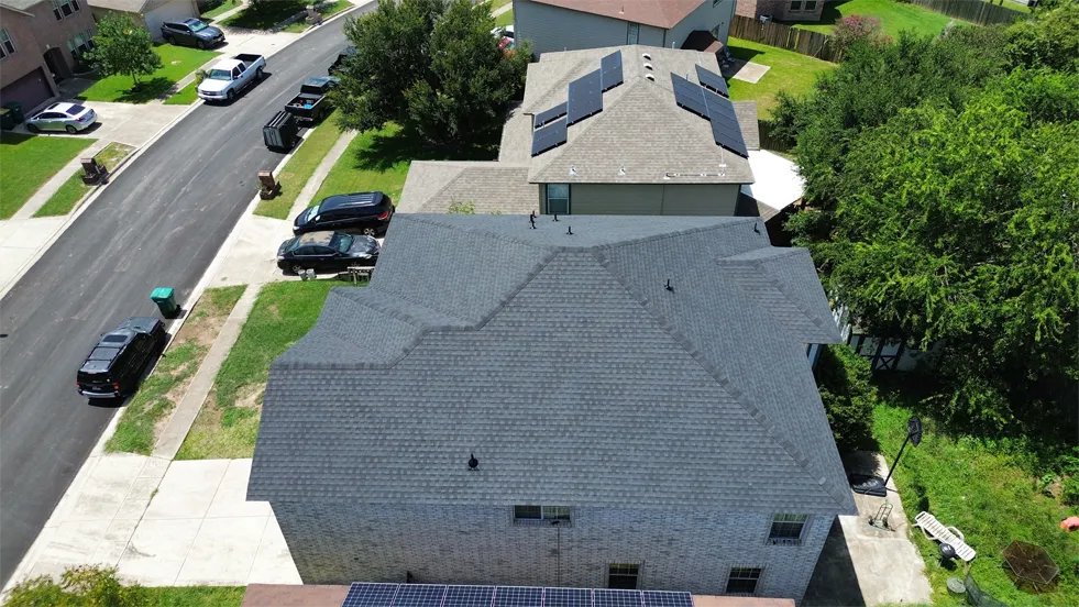 Aerial view of a completed roof, tree-lined residential street