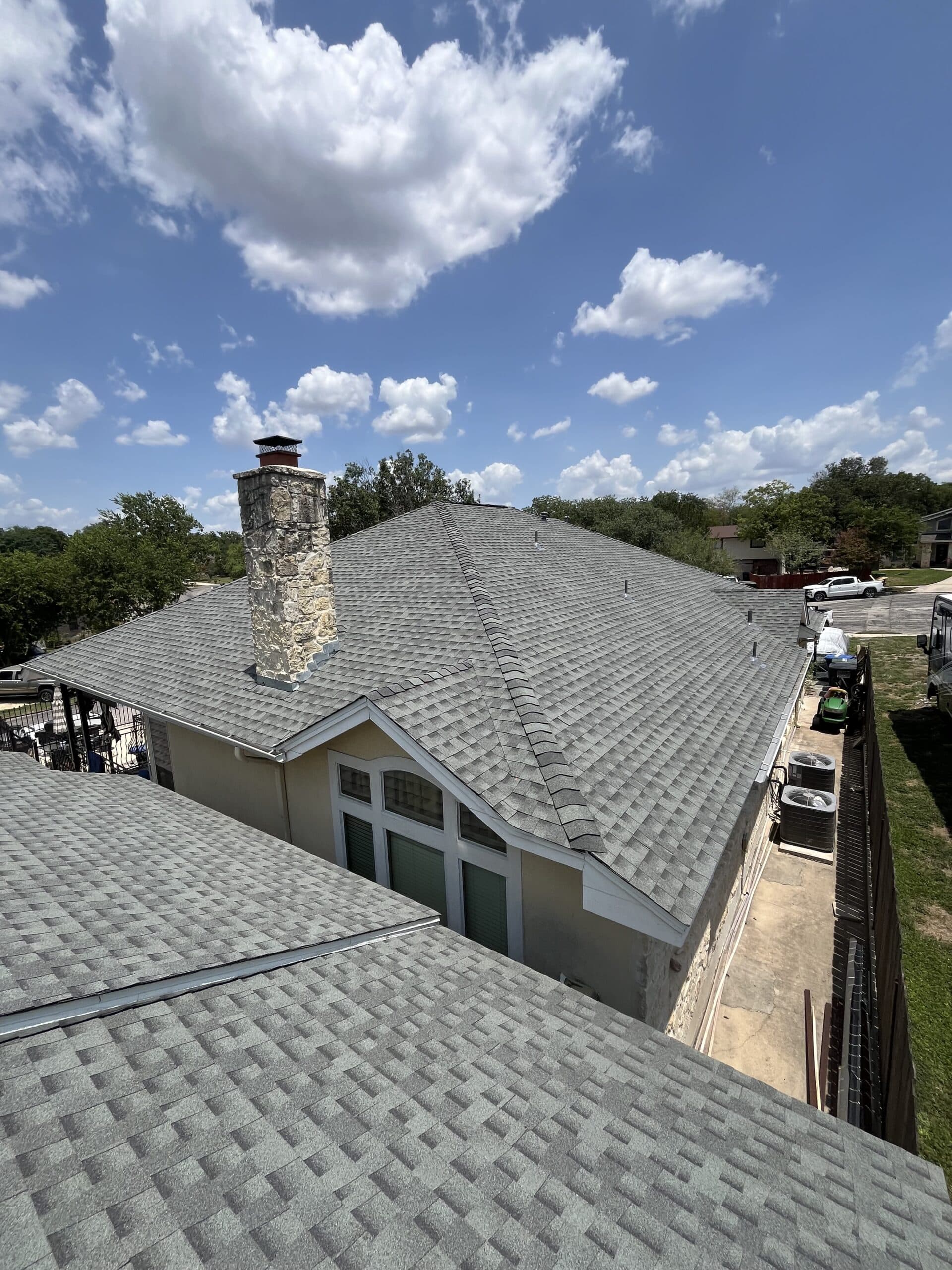 Aerial view of a completed roof with a prominent chimney and mature tree canopy