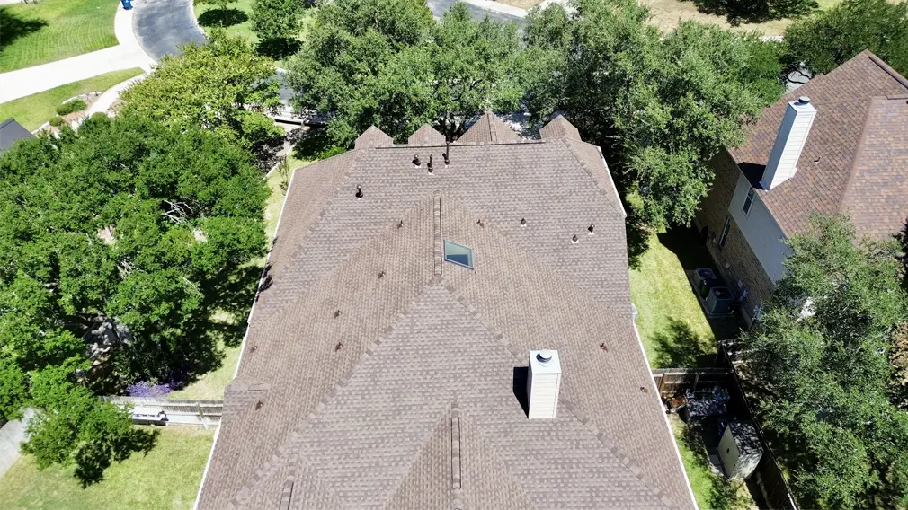 Aerial view of a completed roof with mature tree canopy