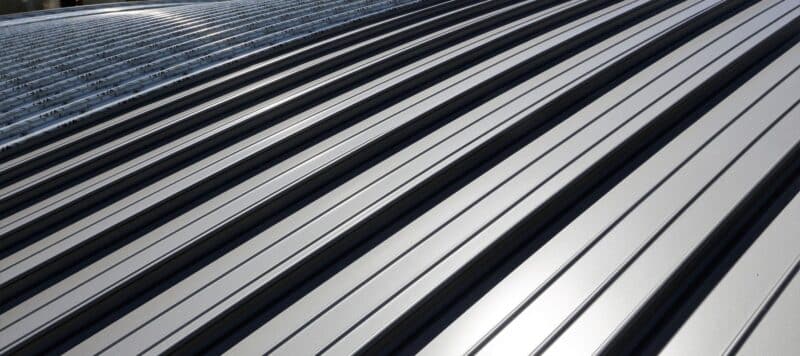 Close-up of a shiny silver metal roof with clean, symmetrical ridges reflecting sunlight