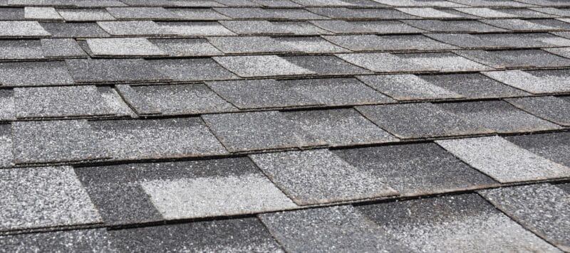 Close-up view of gray asphalt shingles with a textured surface for durability and weather resistance