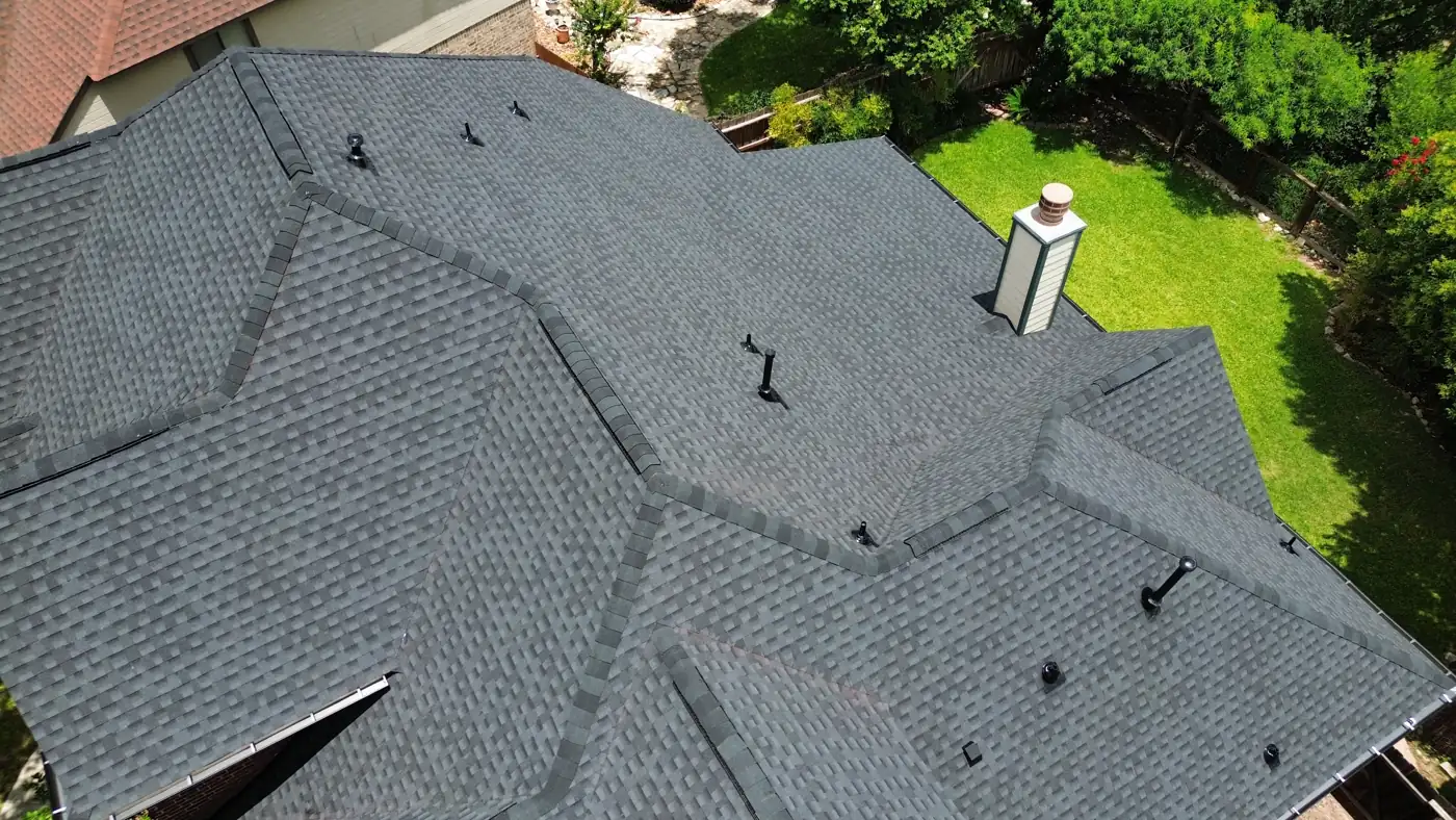 Ridge lines and chimney detail on a new charcoal architectural shingle roof in Helotes, TX by Holmes Roofing, June 2025