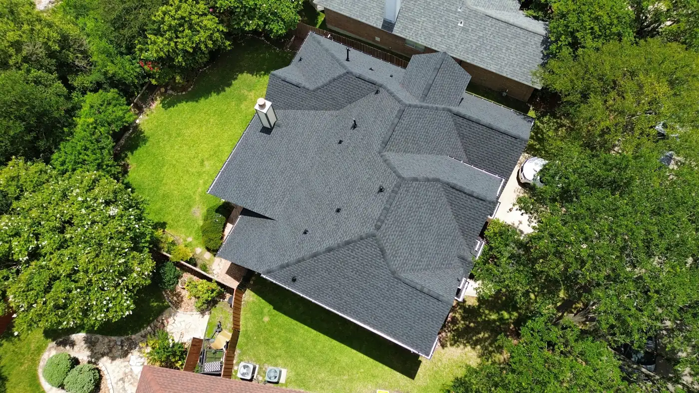 Drone aerial of a completed charcoal architectural shingle roof replacement on a large hip-and-valley home in Helotes, TX by Holmes Roofing & Exterior Solutions, June 2025