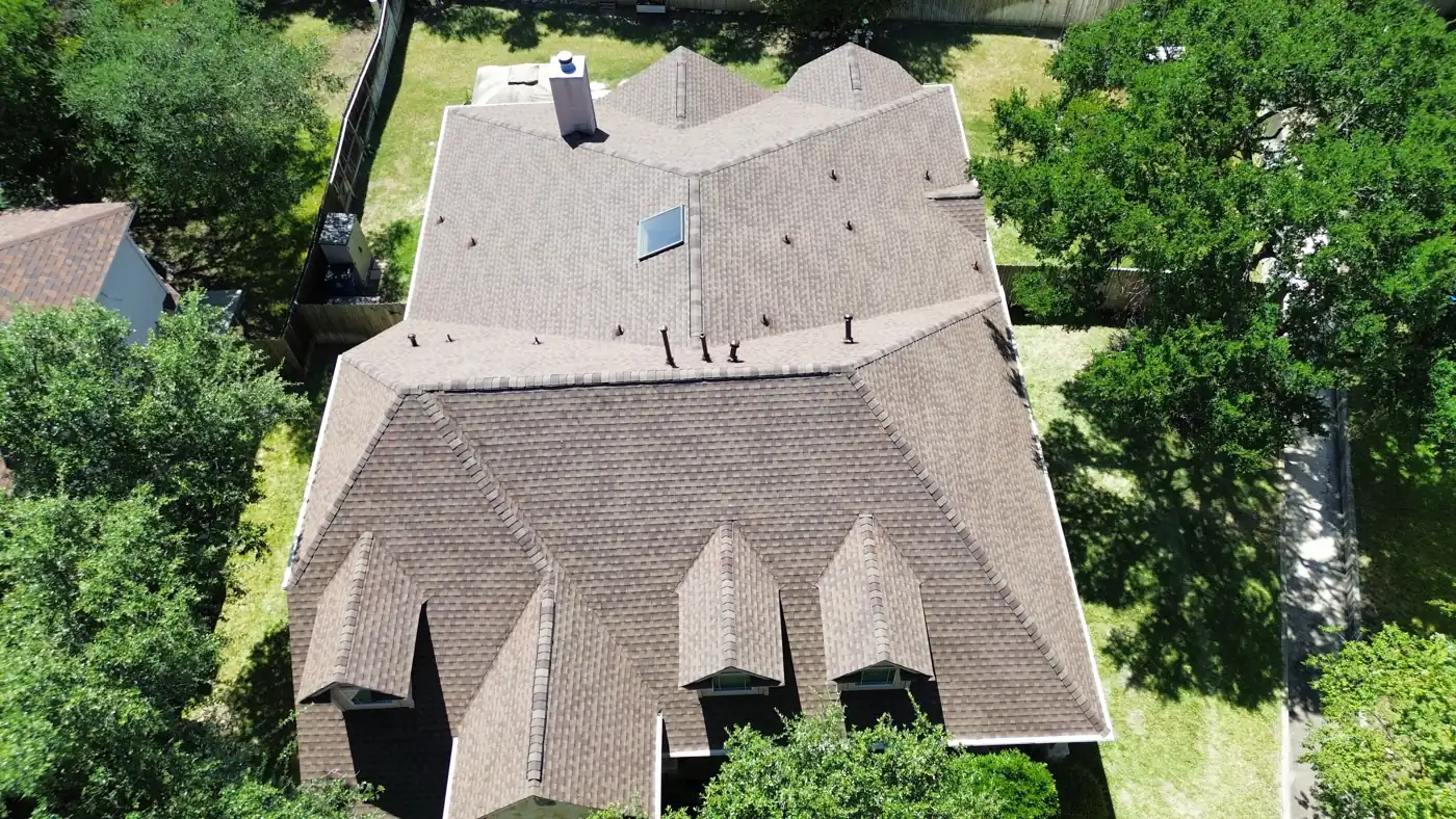 Top-down drone view of a completed brown architectural shingle roof with skylight in Stone Oak, San Antonio, TX, July 2025