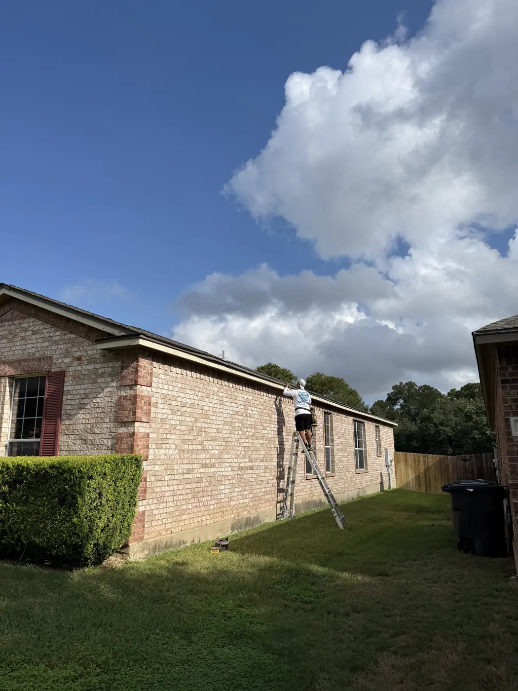 Holmes Roofing crew working at the gutter line of a single-story brick home in northwest San Antonio, TX, September 2025